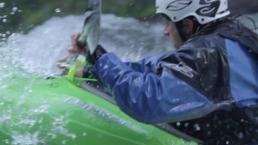 Tight slow motion shot of a whitewater kayaker paddling down a waterfall on a pristine and clear water creek deep in the wilderness