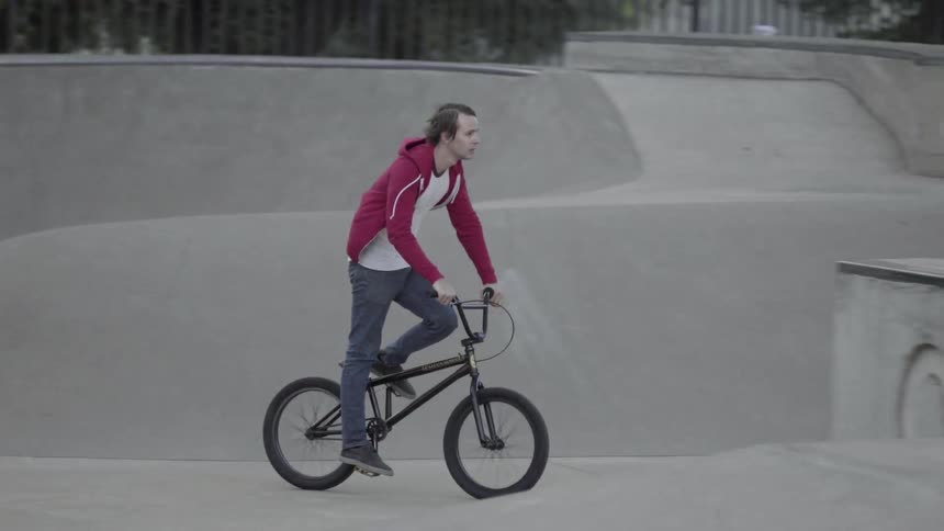 A man rides his bicycle through a skate park