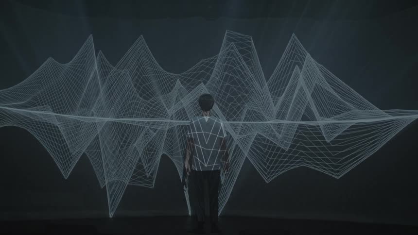 Graphics are projected onto a man's back and the wall in front of him