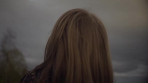 A young girl looks up at a bunch of balloons in the sky