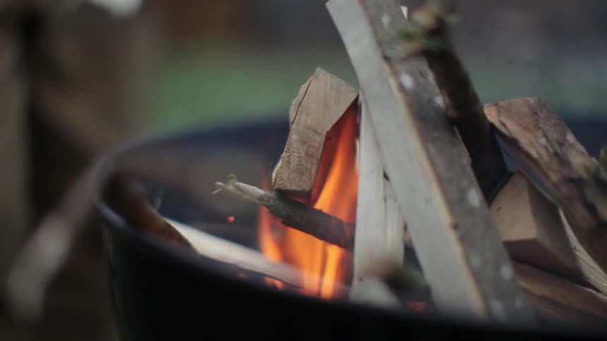 A man blows on an outdoor fire