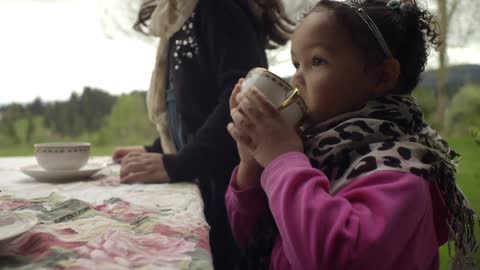 Little girl in pink pretends to drink from a cup