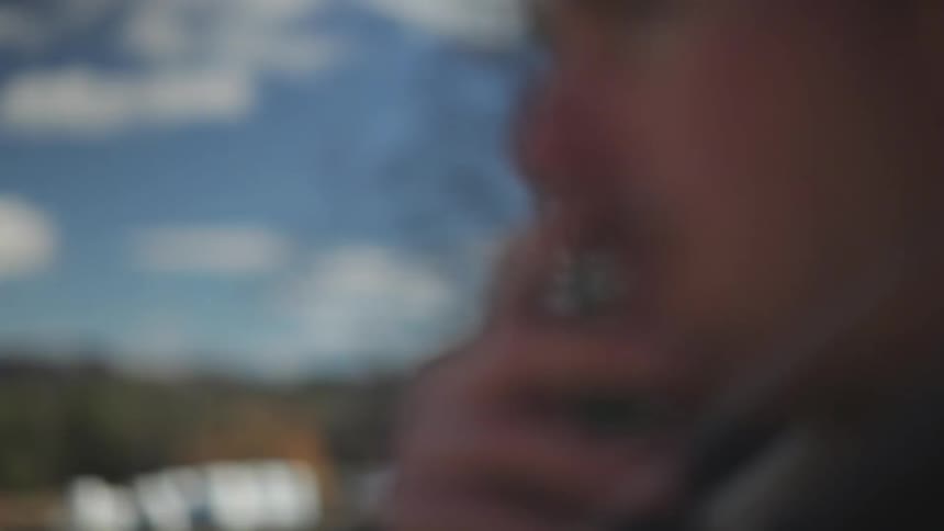 A man smokes a cigarette and exhales smoke