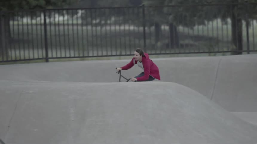 A bicyclist jumps and rides through a skate park