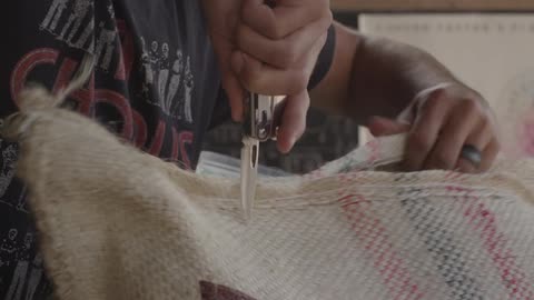 Man cuts open a cloth bag with a knife