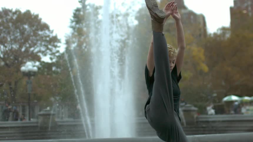 A woman is dancing in front of a fountain