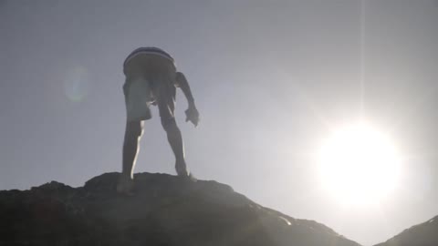 A boy climbs up a hill while the sun blares