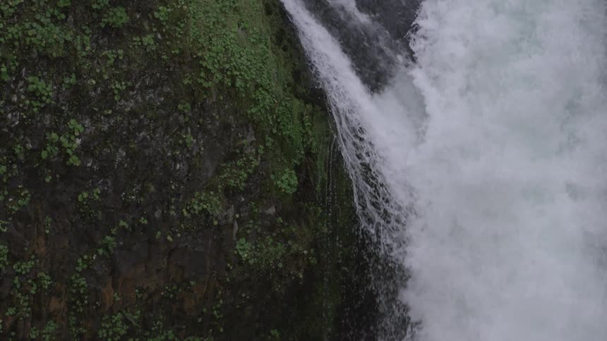 Static shot of the lip of a massive waterfall as the water plunges 100 feet to the pool below