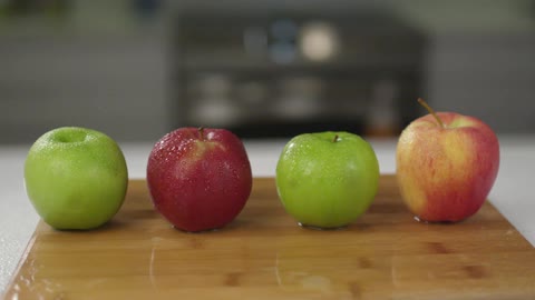 Two red and two green apples on cutting board