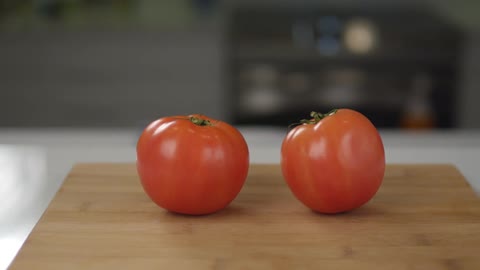 Two red tomatoes on a cutting board