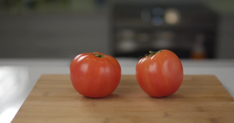 Two red tomatoes on a cutting board