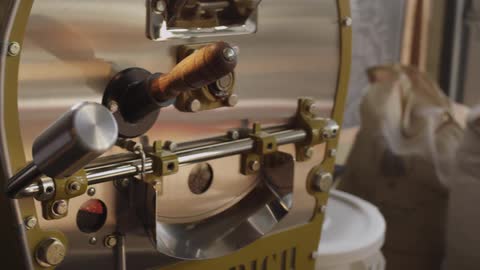 A person inserts a spade type tool filled with something into a larger machine