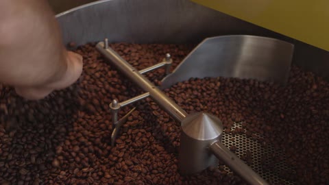 Man and machine mix coffee beans