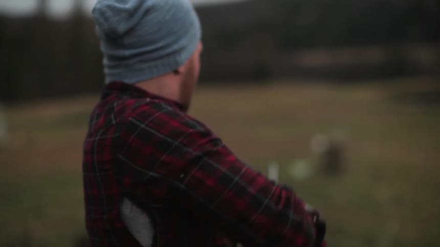 A man in a plaid shirt fires a gun