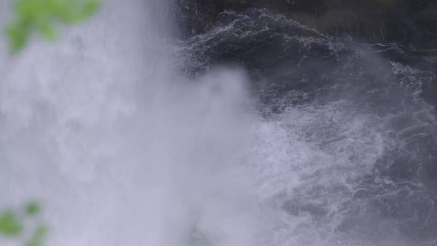 Tight static shot of Metlako Falls crashing into the river pool at the base of the waterfall