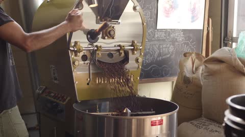 A man operates a coffee bean roasting machine