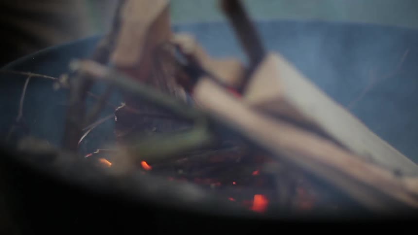 An outdoor fire burns and smokes