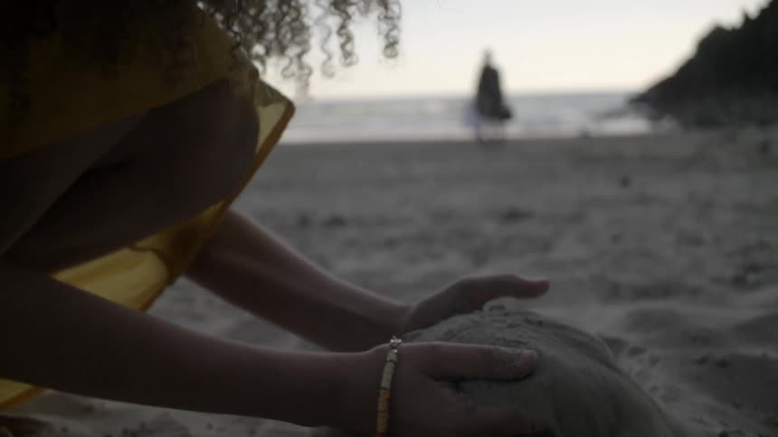 A girl scoops up sand on the beach