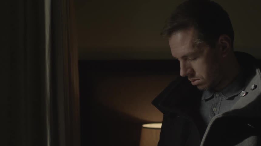 Man in coat looking out of window
