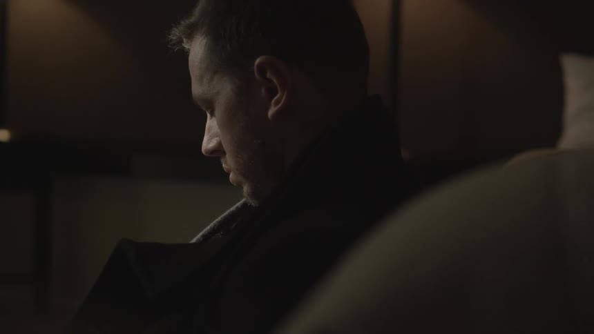 A man sits on the floor of a bedroom
