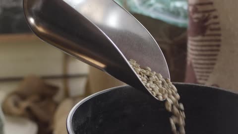 A man scoops coffee beans from a bin