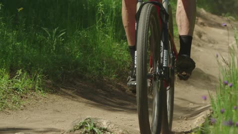 Man biking down a dirt bath next to flowers