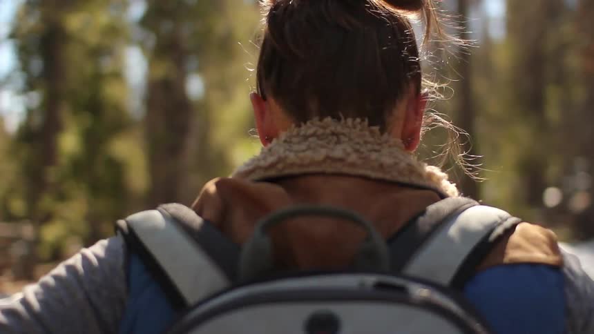 Woman is hiking through the woods with a backpack