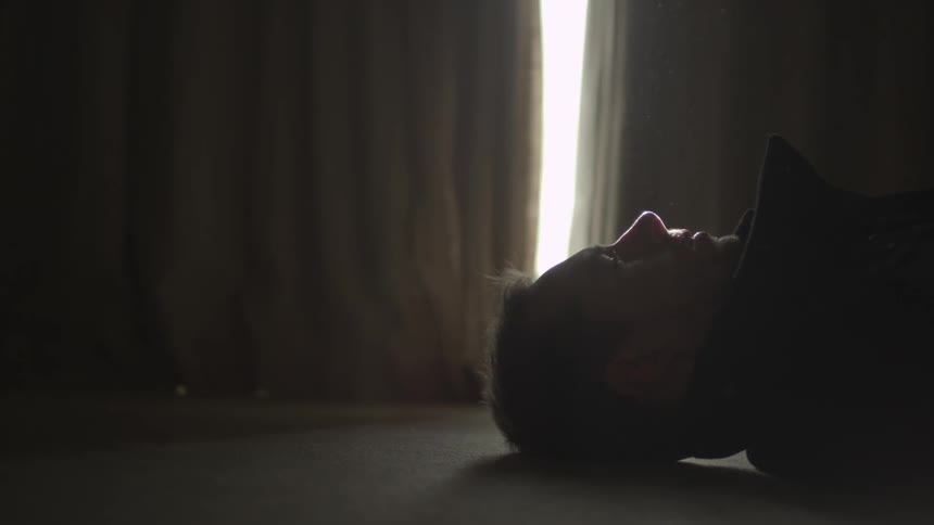 A man laying on the floor with his head to his right side, then he rolls his head to face up