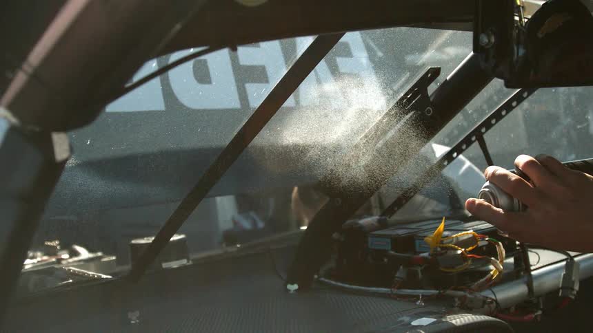 A person spraying the windshield of a vehicle