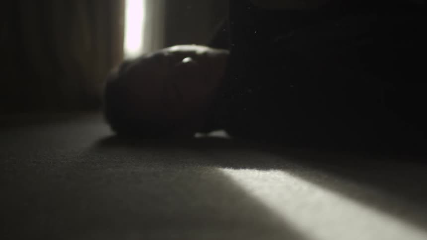A blurry view of a man laying on the floor with his head to his right side