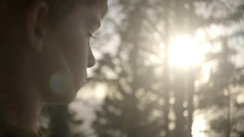Young boy in a wooded area near sunset