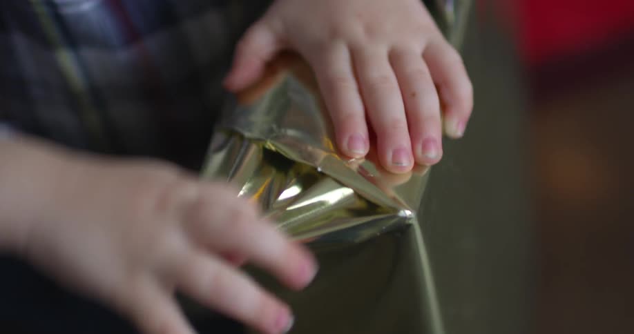 A child tries to tear off the wrapping paper on a box