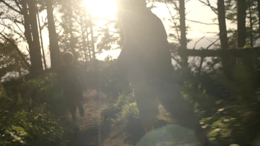 Boys run through forest trail