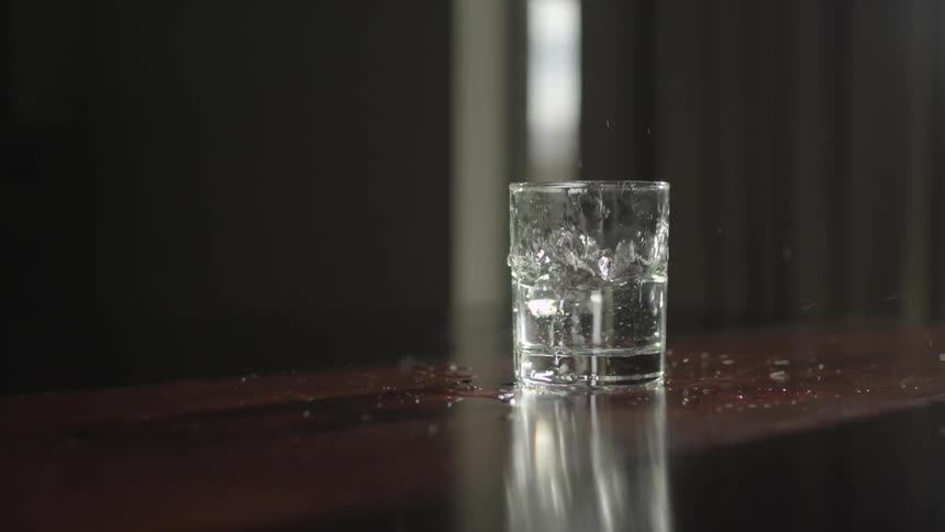 Glass spills water when wood table shakes