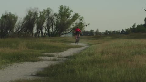 A cyclist riding his bicycle across open grasslands