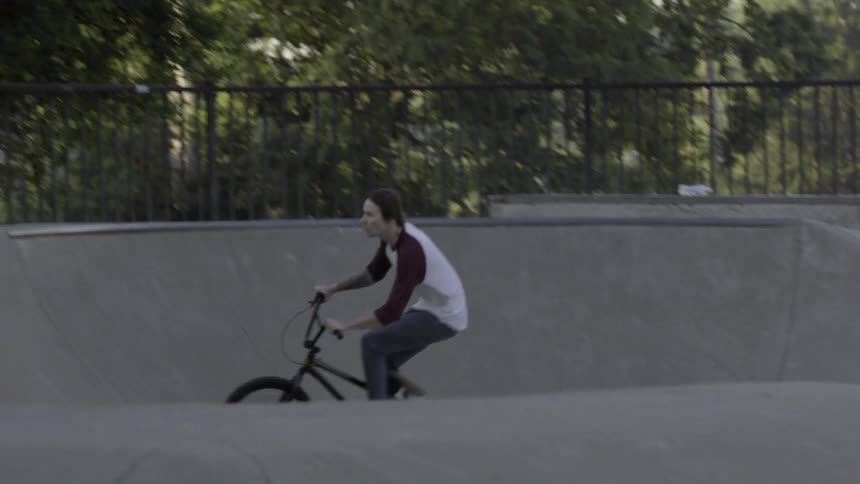 A man bicycles through a skatepark