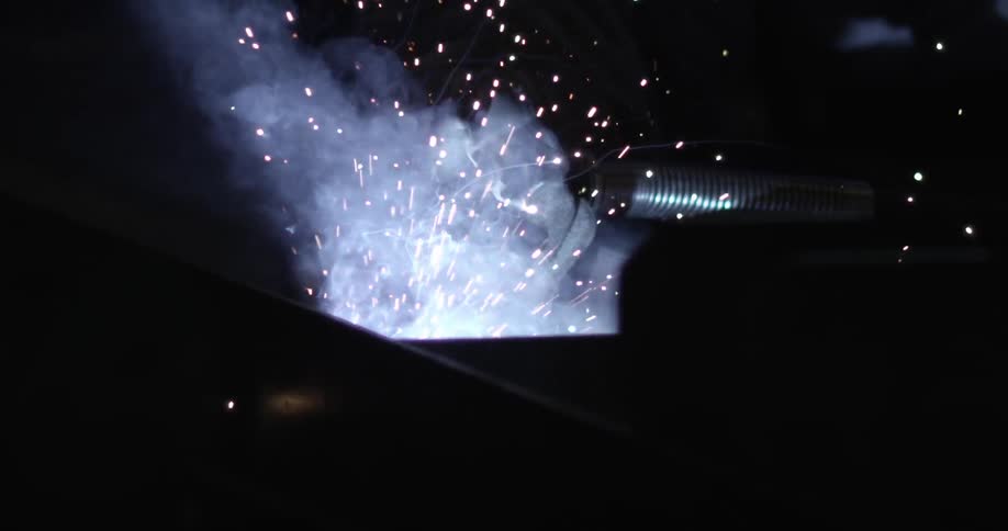 Sparks and smoke fly while a welder works