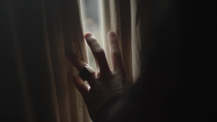 A person running their hand over a curtain