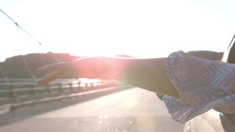 Woman waves her arm up and down outside a car window in slow motion