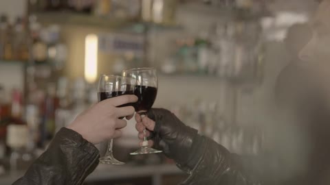 Two people clinking their wine glasses together before taking a sip