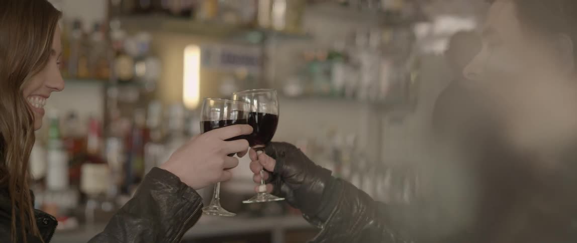 Two people clinking their wine glasses together before taking a sip