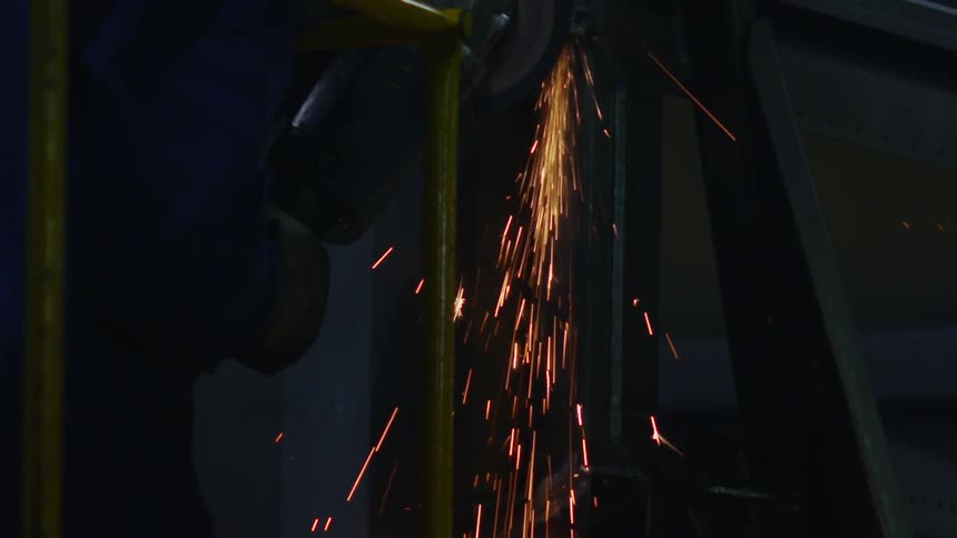 Sparks flying as a man sands a metal bar