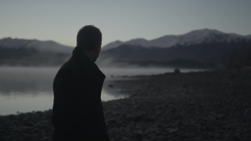 Man standing and pondering near an eerie lake