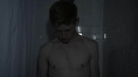 A man stretching his neck stands in a shower