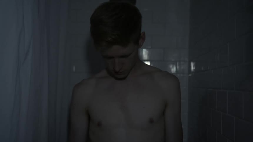A man stretching his neck stands in a shower