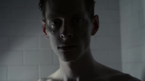Lights flash showing a man standing before a white brick wall
