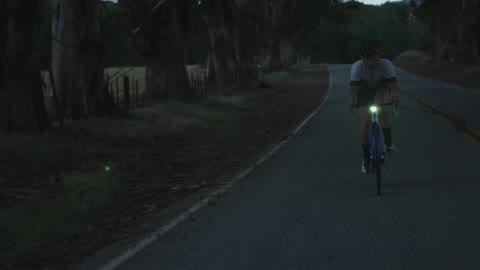 Man bikes down a dark road