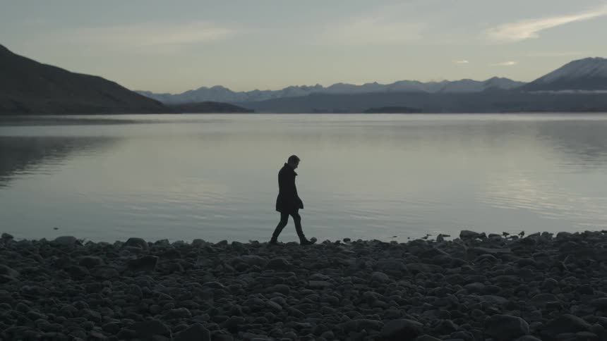 A person walking along a rocky shoreline