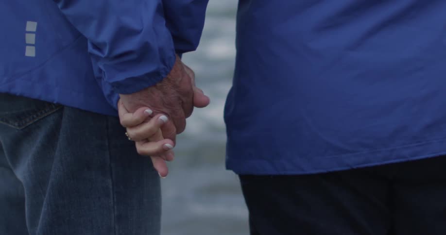 A couple holds hands while standing near a body of water
