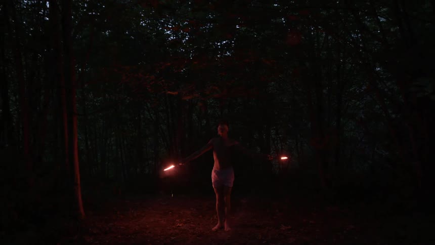 A person with flares standing in the woods
